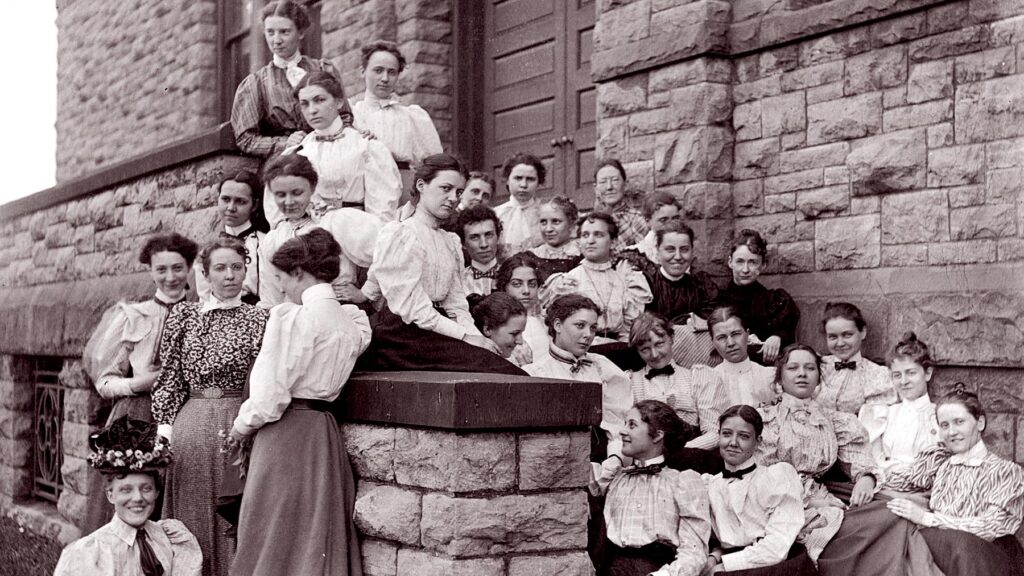 women sitting outside historic building 1887