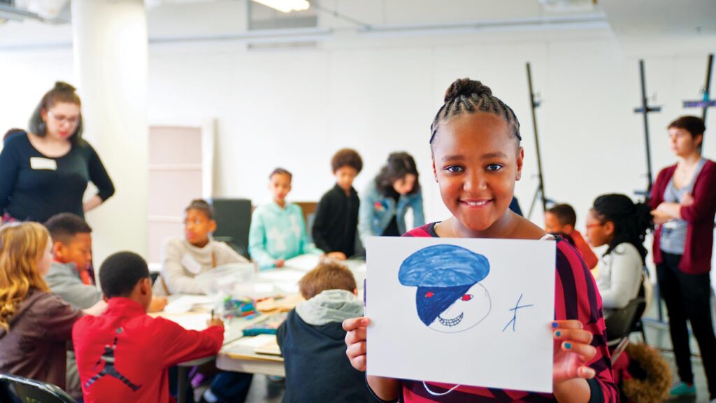 elementary school girl holding up drawing