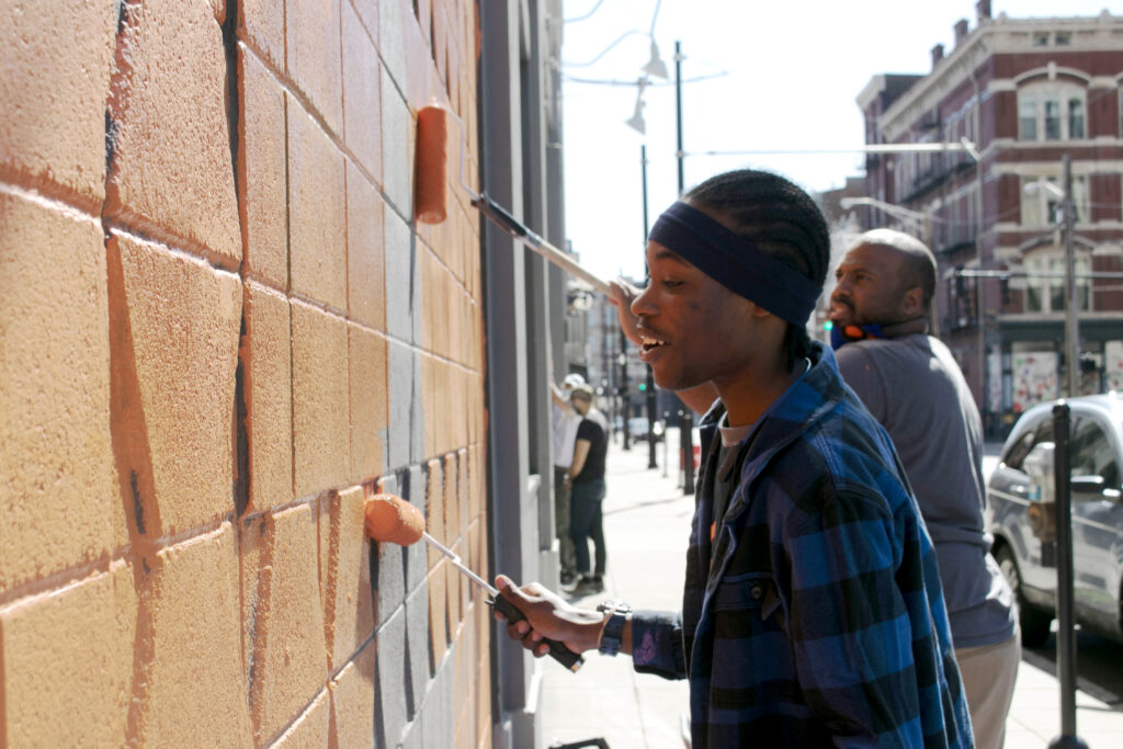 student and faculty painting a wall