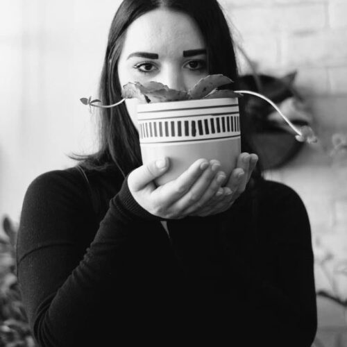 black and white headshot of woman holding a plant