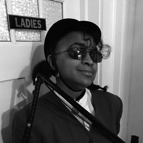 black and white headshot of woman with hat and sunglasses