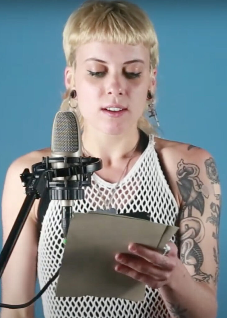 student with tattoos reading into mic