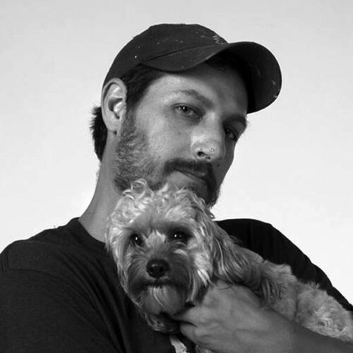 black and white headshot of man with hat holding dog