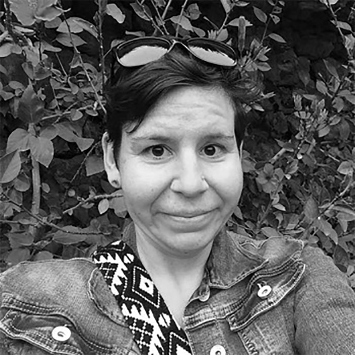 black and white portrait of woman smiling outside in front of plants