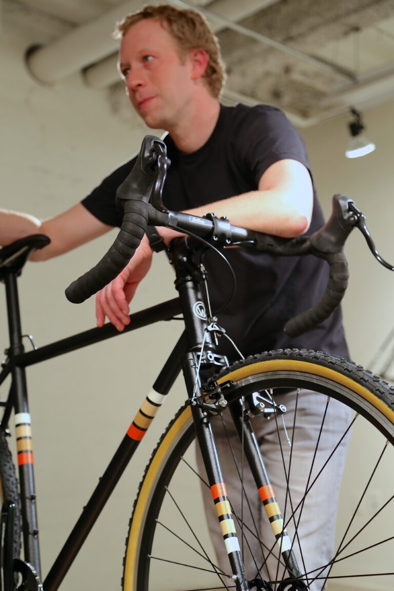 man standing over bicycle