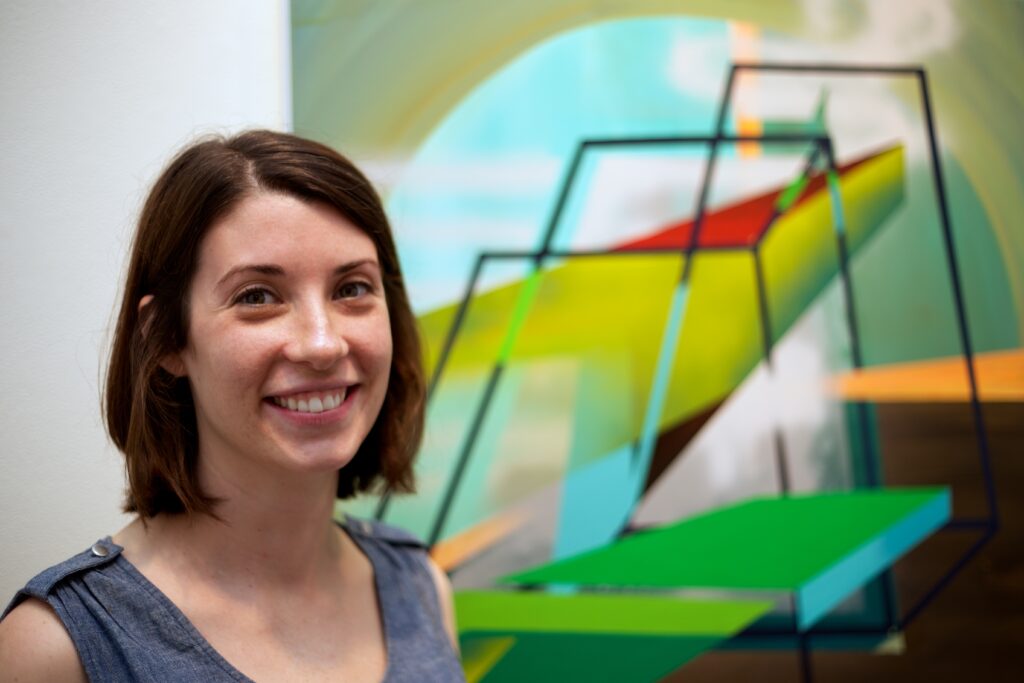 woman smiling in front of green geometric painting