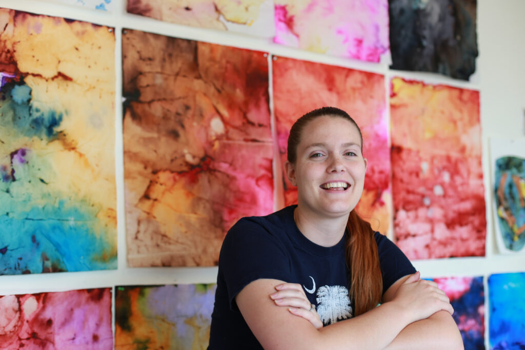 woman posing in front of colorful dyed paper abstract paintings