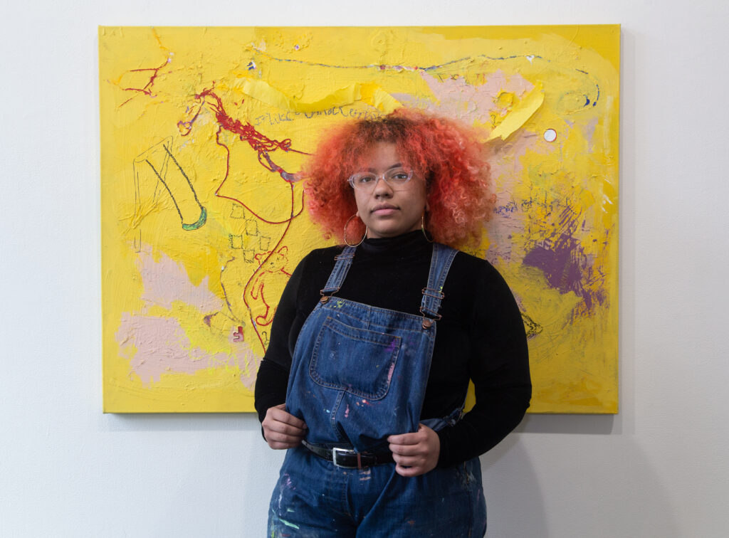 artist standing in front of yellow painting