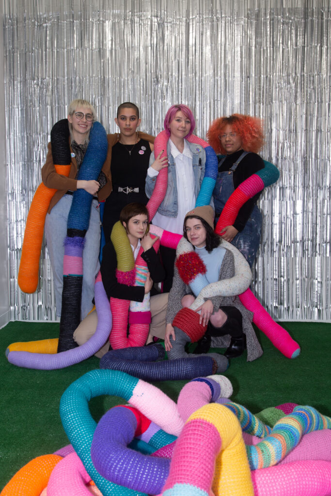 students posing wrapped in long knit pillows