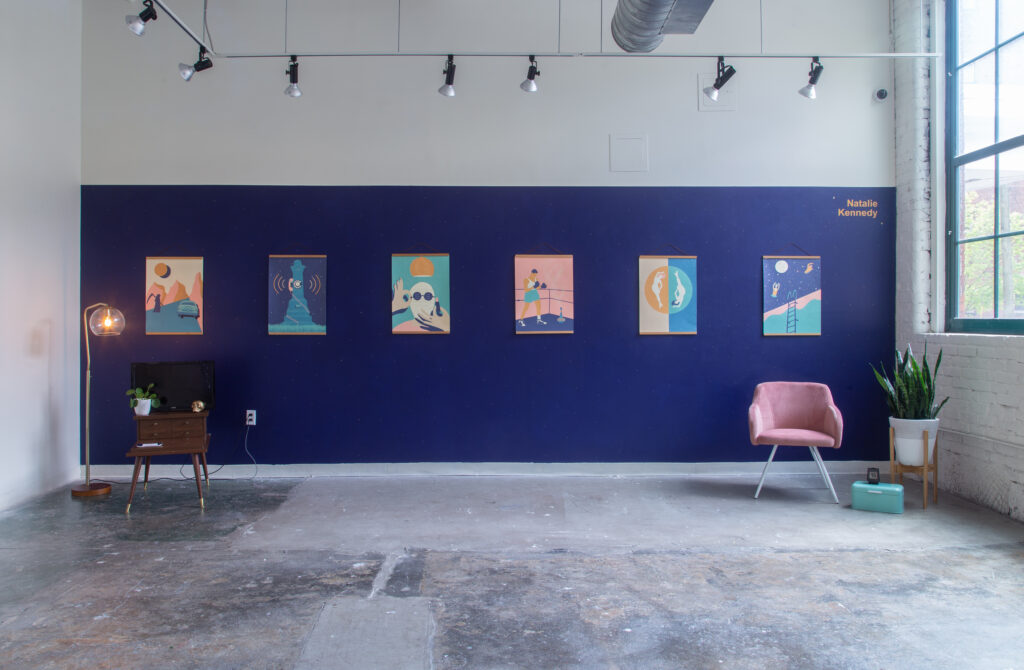mid-century styled gallery with six teal and pink posters with chair, lamp and plants