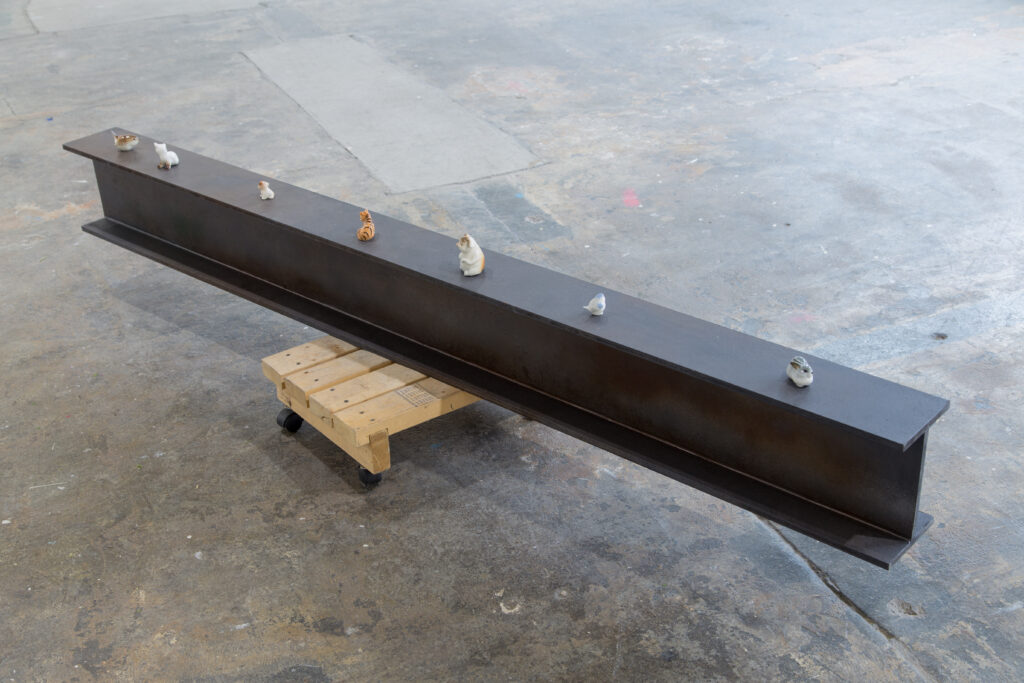 large metal beam with small ceramic animals placed on top