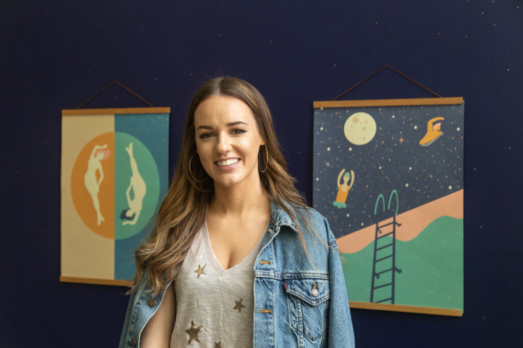 woman standing in front of blue wall will posters