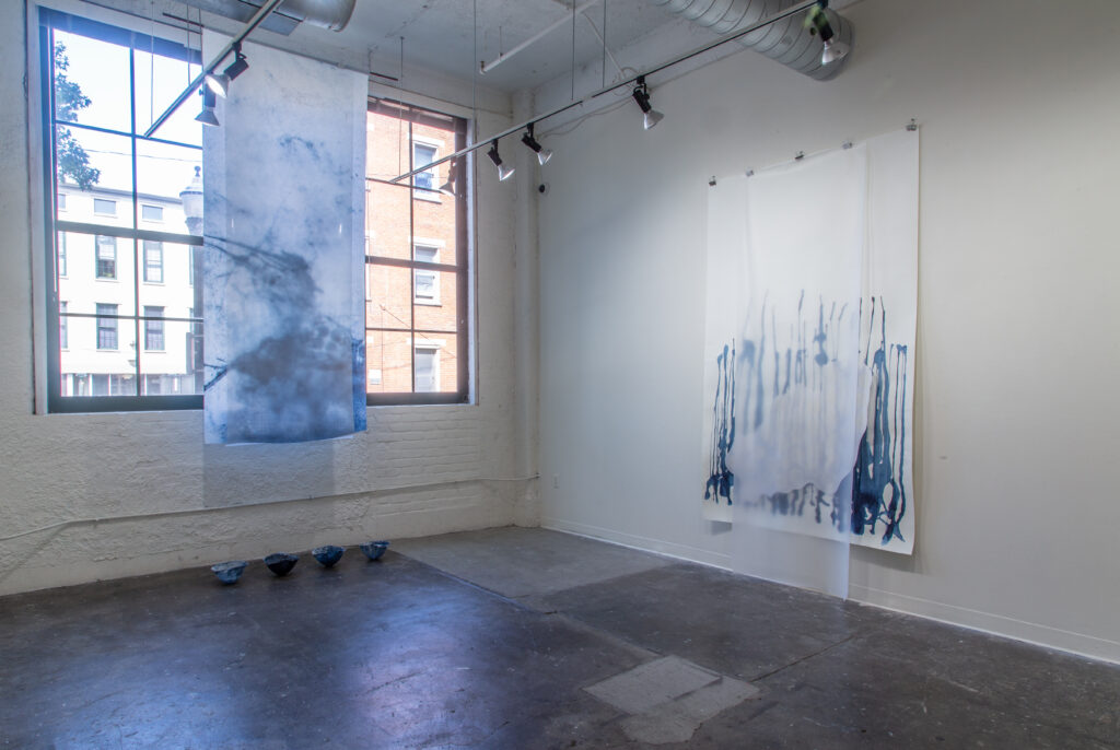 hanging blue paper work, and large blue wall paper work in gallery