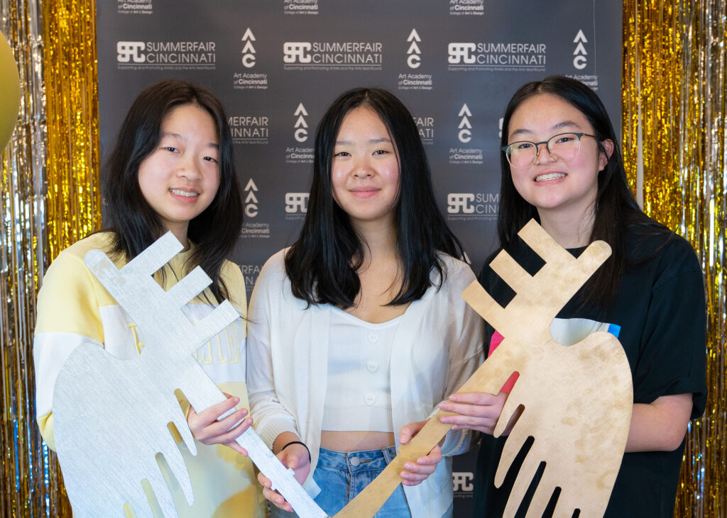 three students holding gold key and silver key