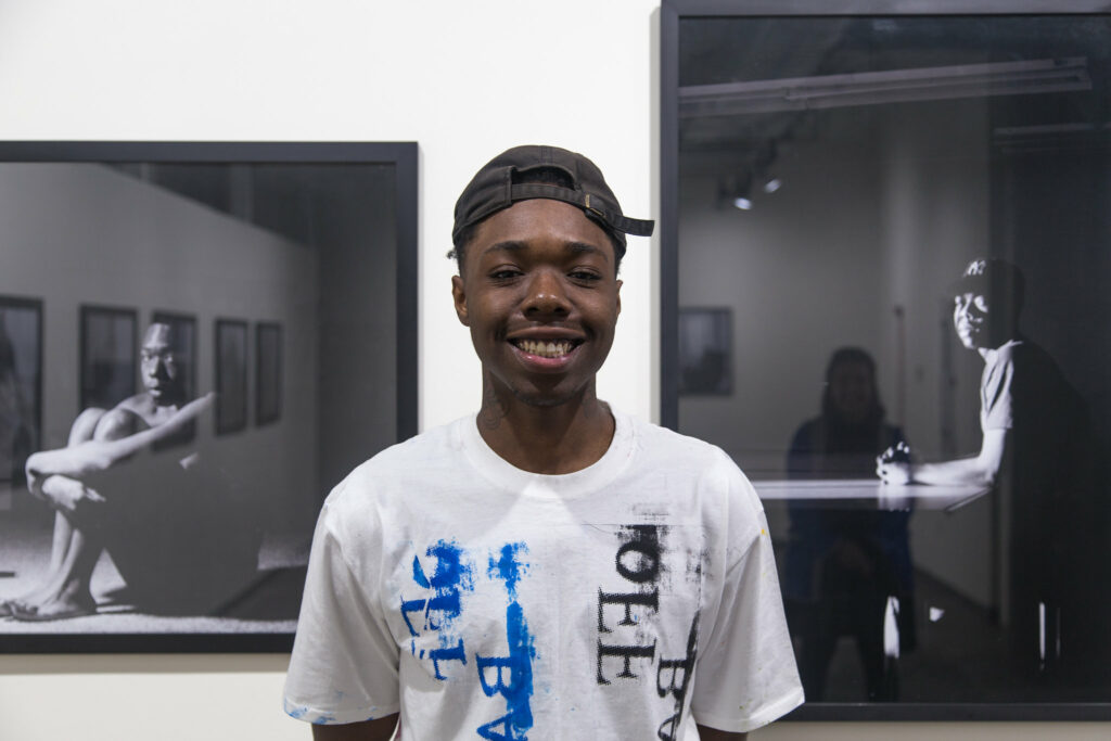 student standing in front of black and white photos