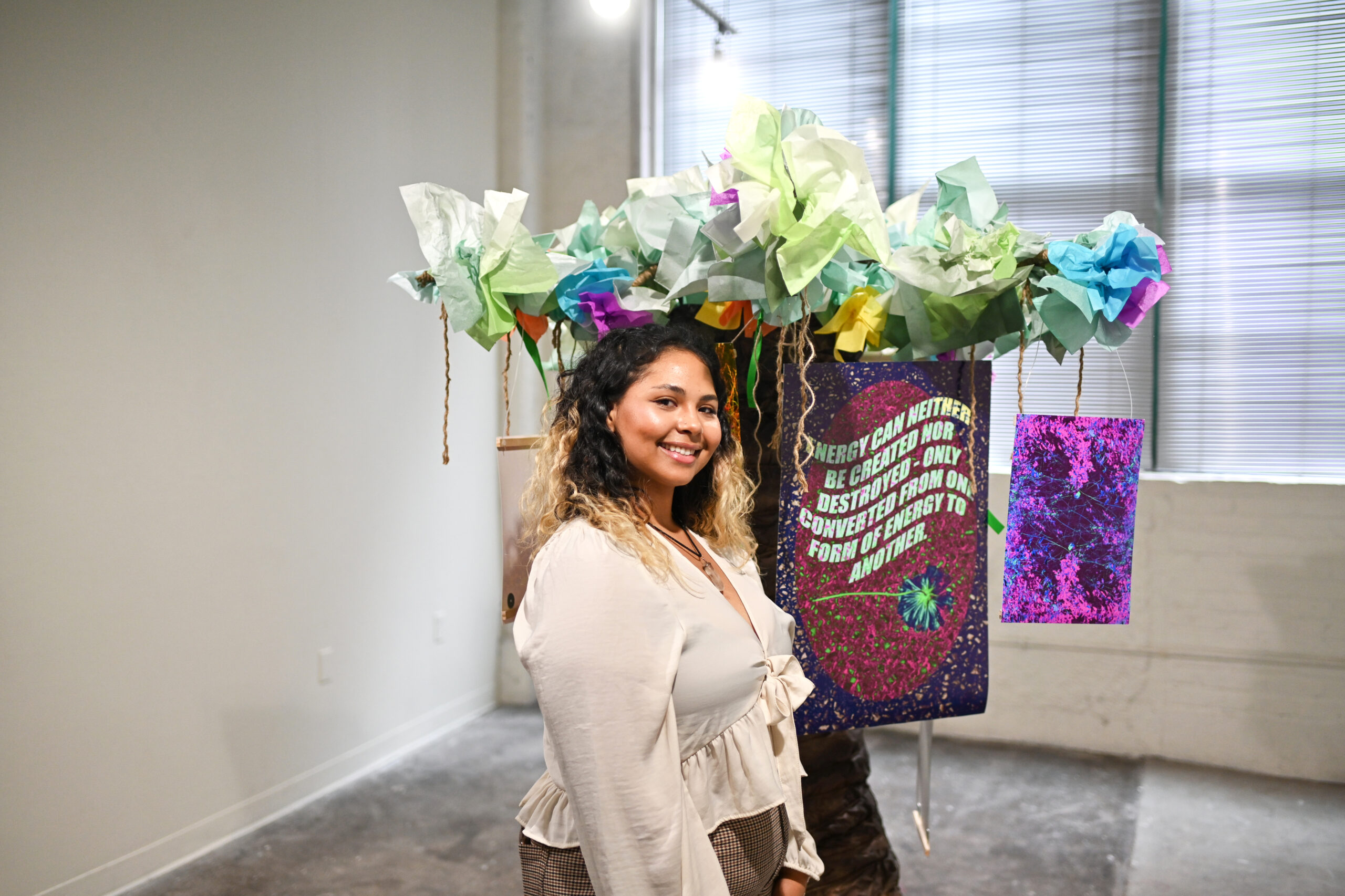 student posing with gallery installation