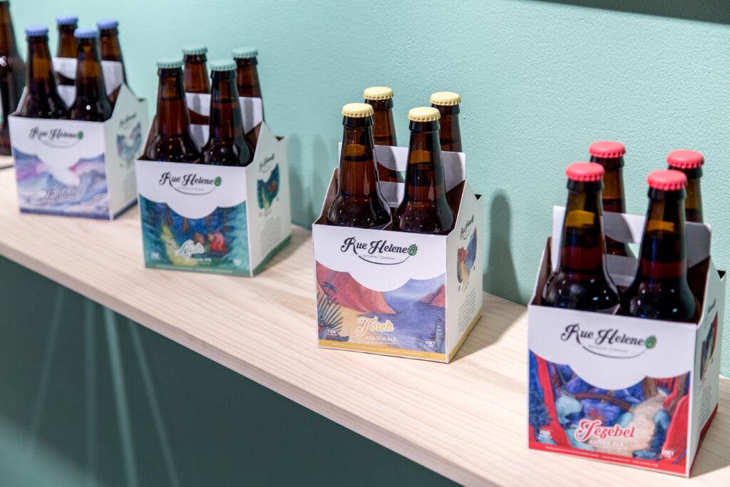 shelf with four packs of beer with package designs of landscapes
