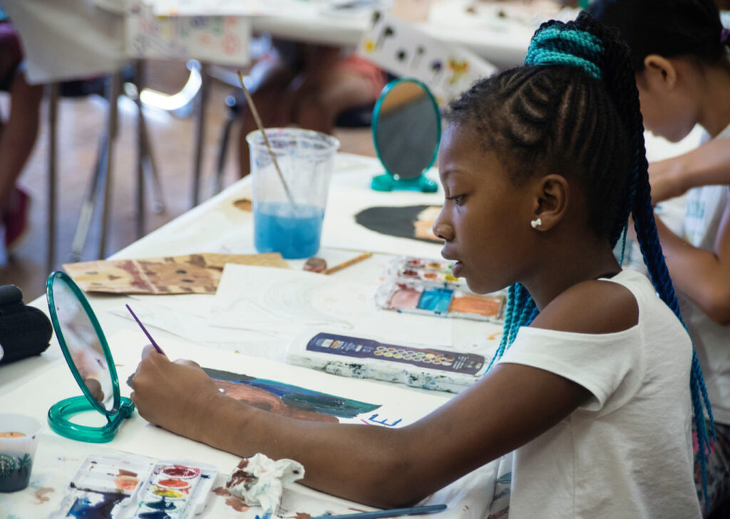 girl painting looking at a mirror