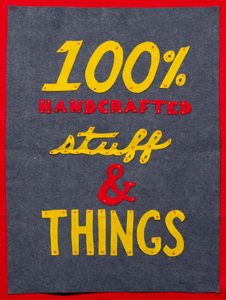 felt poster in gray, red, and yellow reading "100% handcrafted stuff & things"