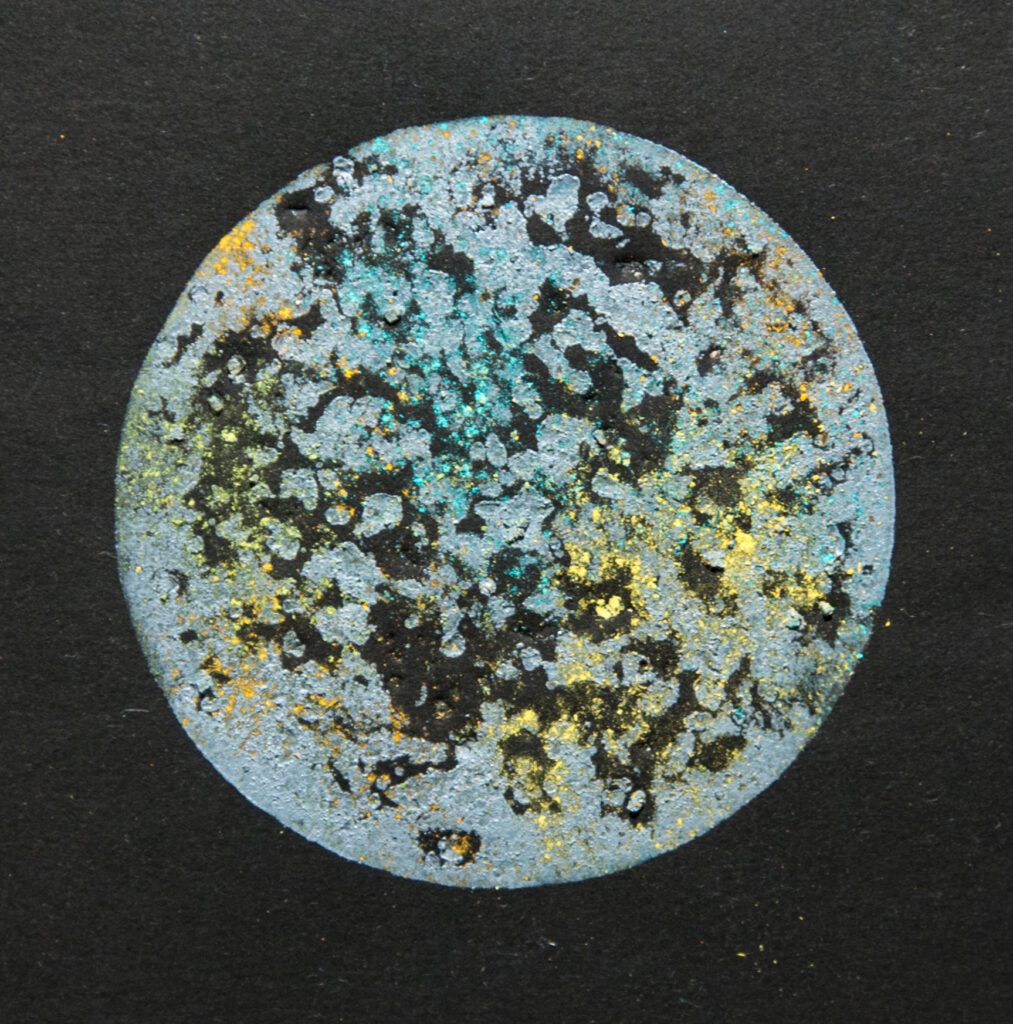 circle of metallic blue and gold inks on black background