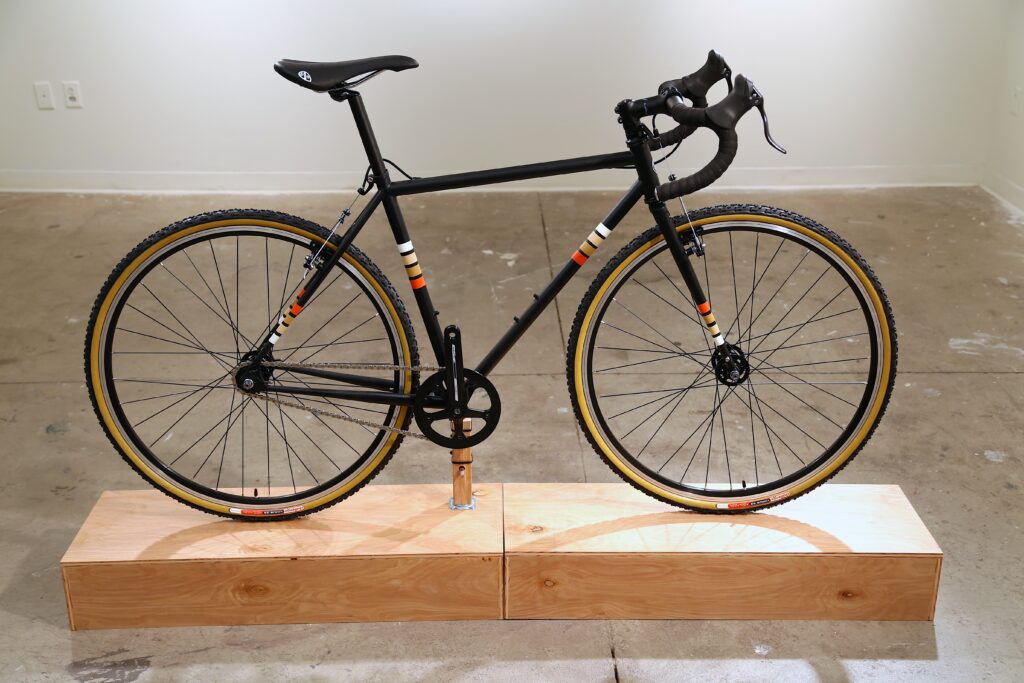 black road bike frame with orange and creme stripes