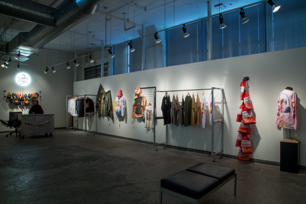 storefront installation of printed clothing and textiles hanging on racks and gallery walls