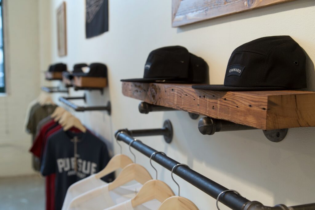 hats and branded shits on wood shelves and steel rail