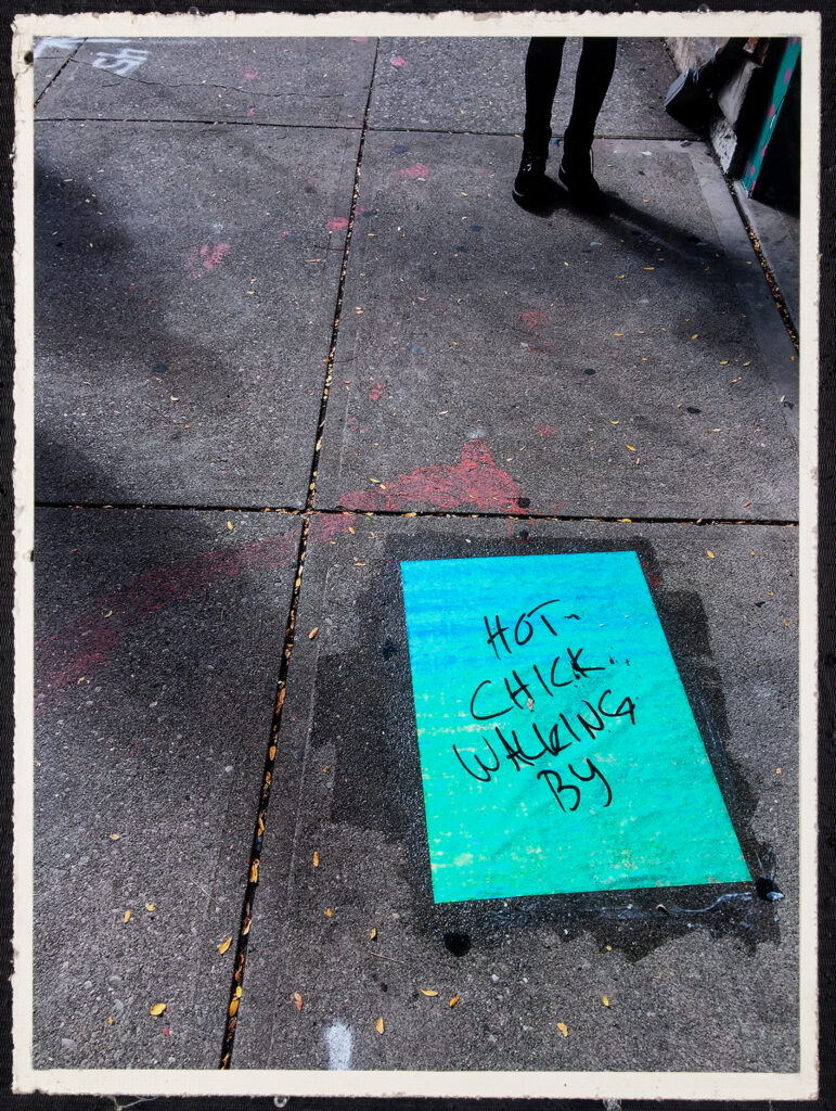 wheat paste of blue glitter paper print reading "hot chick walking by" on the sidewalks