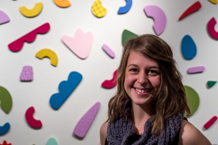woman standing in front fun colorful shapes on wall