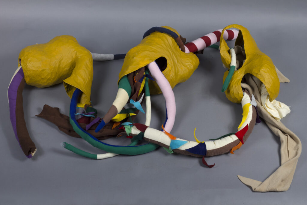 stuffed fabric sculptures emerging from yellow paper maché forms