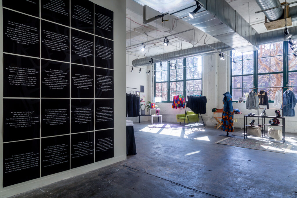 gallery with black grid of digital text prints and clothing shop