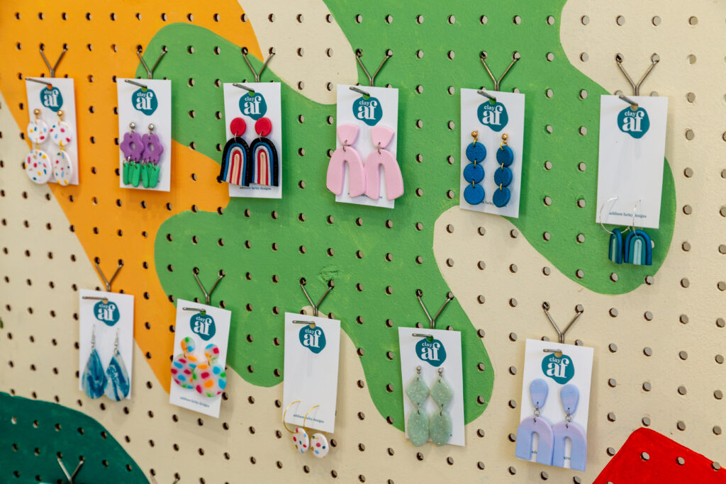 detail of ear rings for sale on colorful pegboard