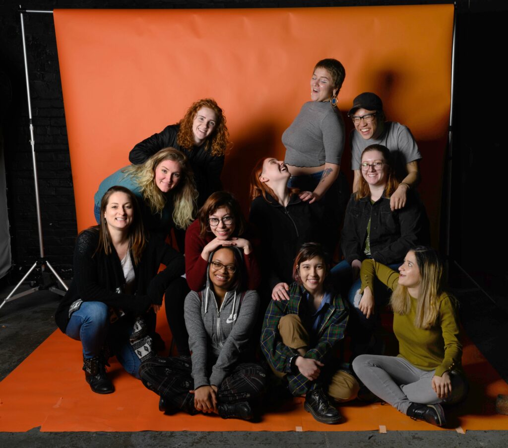 students posing in front of orange backdrop in photo studio