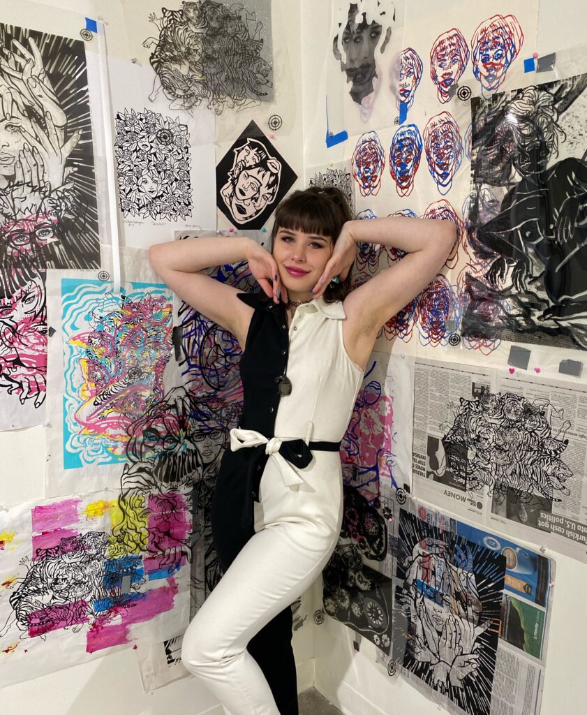 student in black and white jumper standing in front of her print work