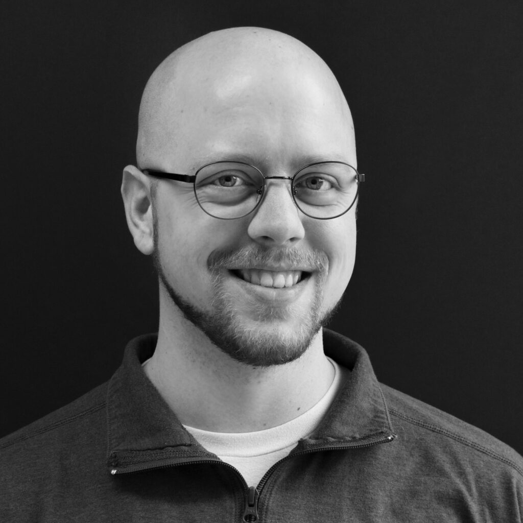 black and white portrait of man with glasses smiling