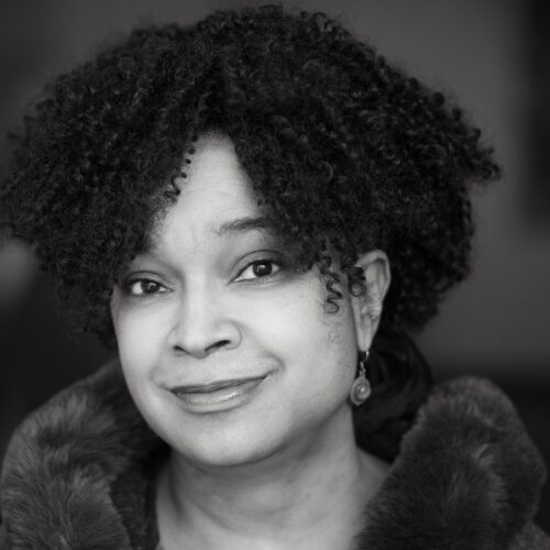 Woman with curls and earrings smiling