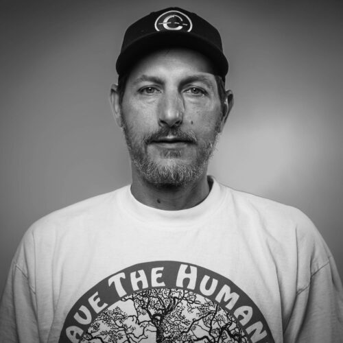black and white headshot of man with hat holding dog