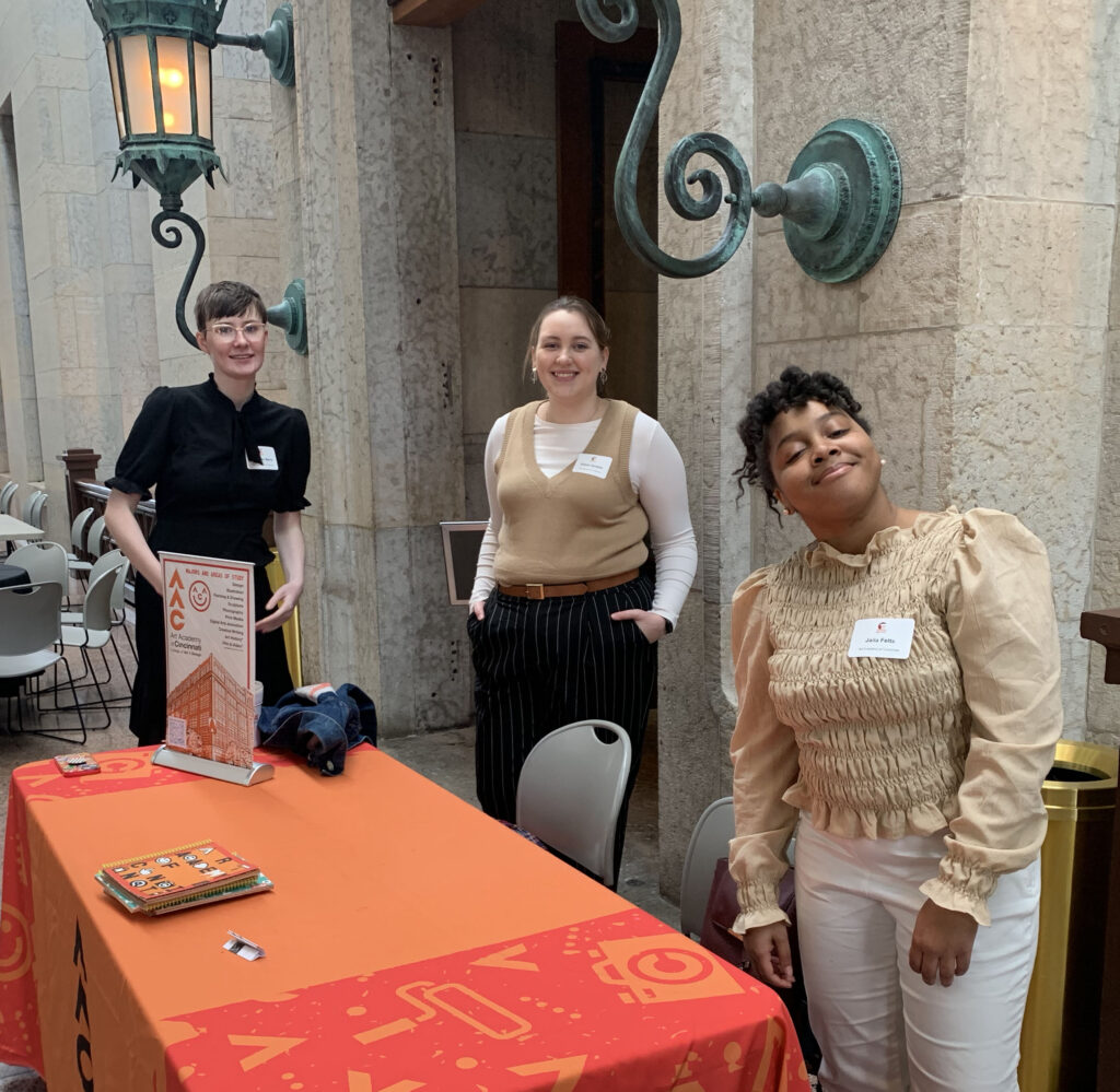 three students standing near a table at a fair