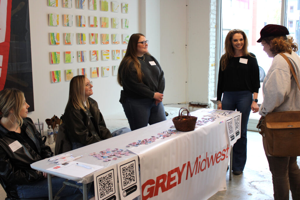 A student speaks with representatives from Grey Midwest at the Spring 2023 Career Fair in SITE1212 at the Art Academy of Cincinnati.