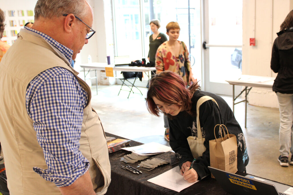 A student gives their information to a prospective employer at the Spring 2023 Career Fair in SITE1212 at the Art Academy of Cincinnati.