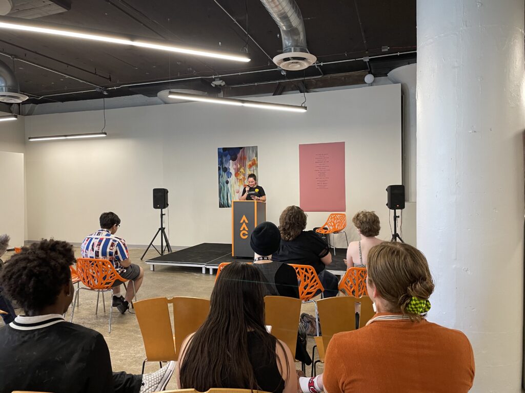 Students sit and listen to a fellow student speaker at the Spring 2023 WAAC literary magazine Release Party in SITE1212 at the Art Academy of Cincinnati.