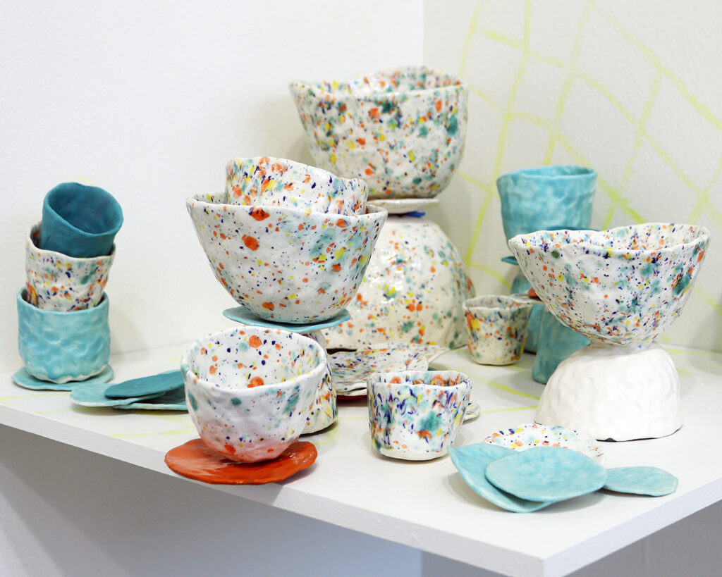 An installation of colorful ceramic cups and sculptural elements