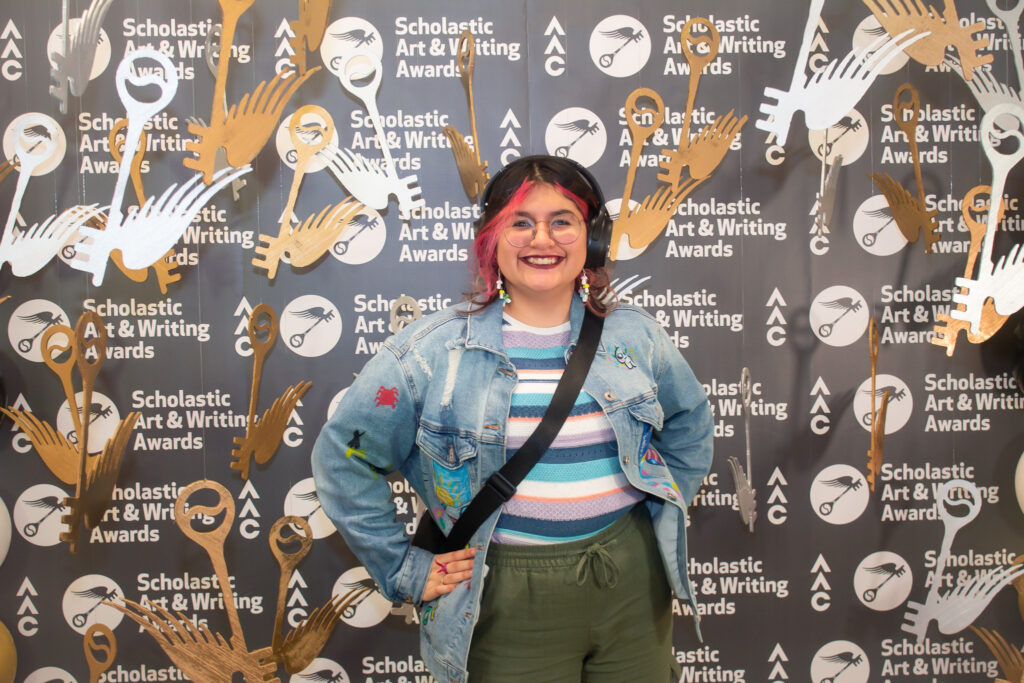 Regional Scholastic Art & Writing award recipient standing in photo booth that includes hanging silver and gold prop keys.