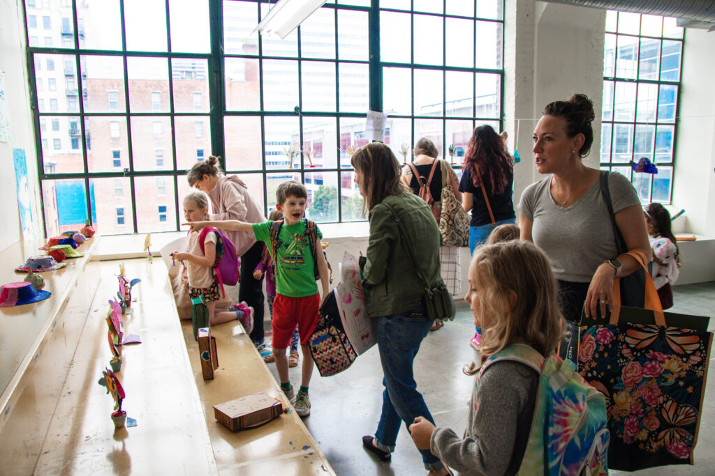 Students with their parents or guardians look at their work in an exhibition.
