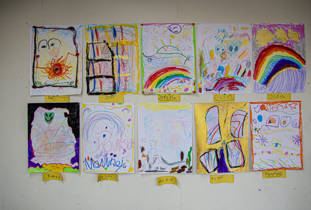 10 2-D artworks made by students displayed on a white wall.