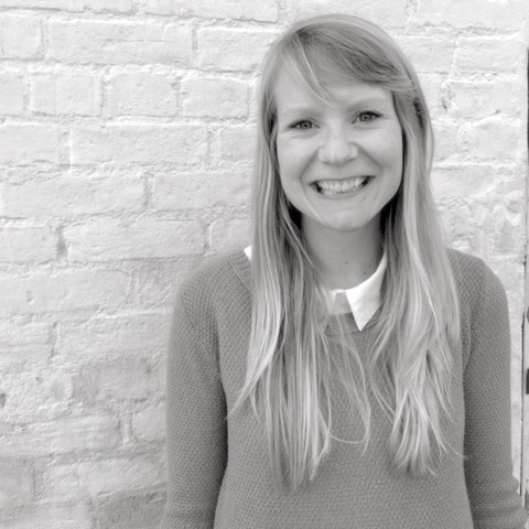 Woman standing by a wall smiling