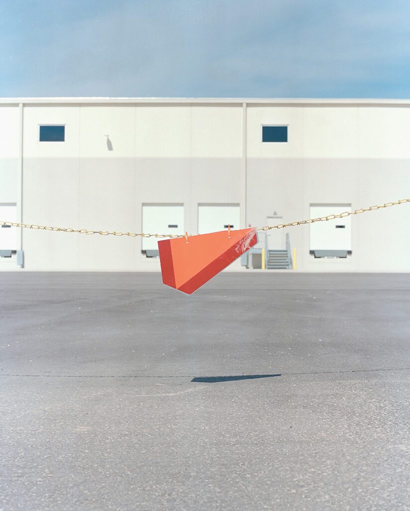 A photograph of a chain barrier in an empty parking lot