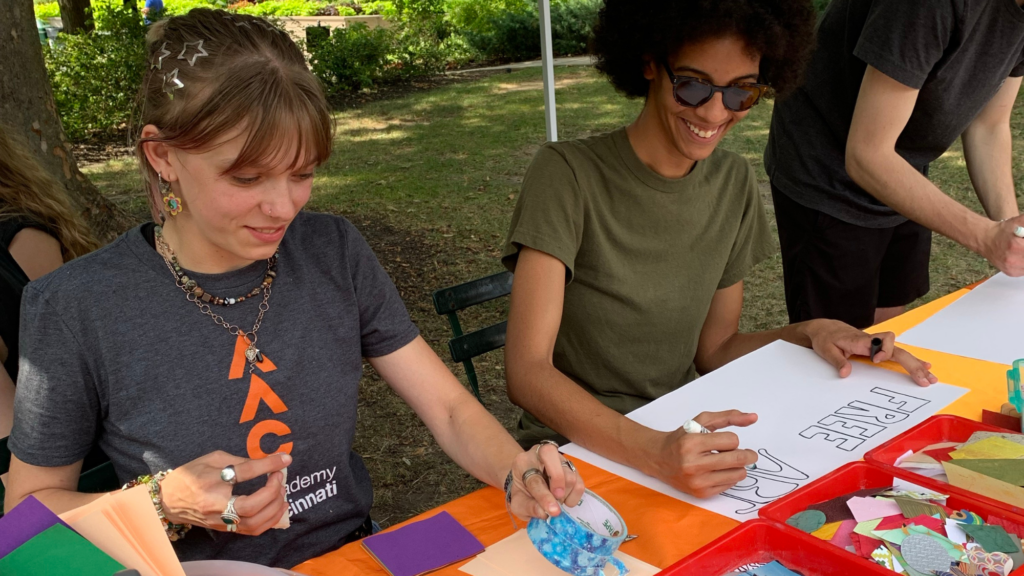 Young white woman and young black man sitting at a table in the park