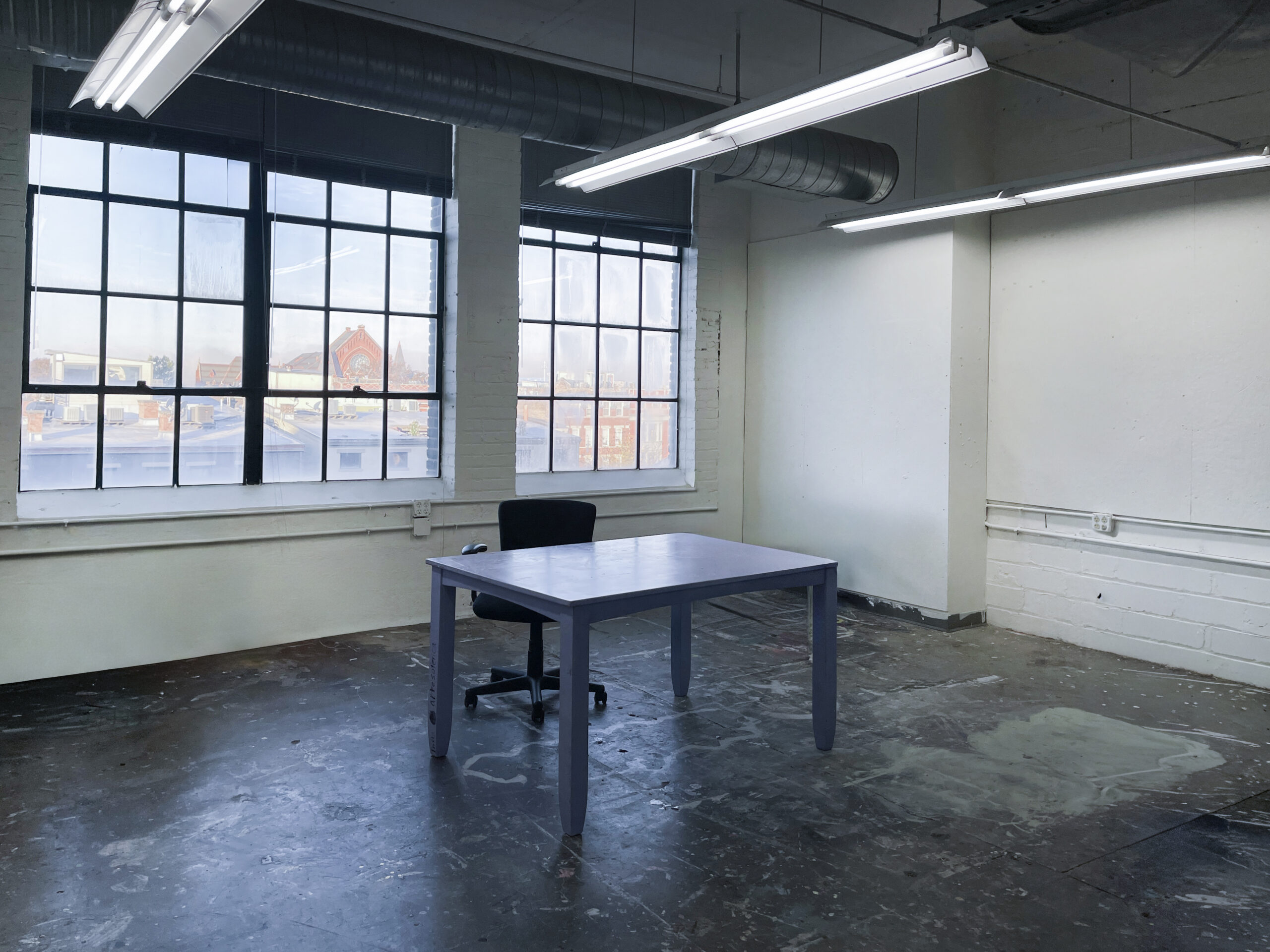 empty artist studio with blank white walls, desk and chair