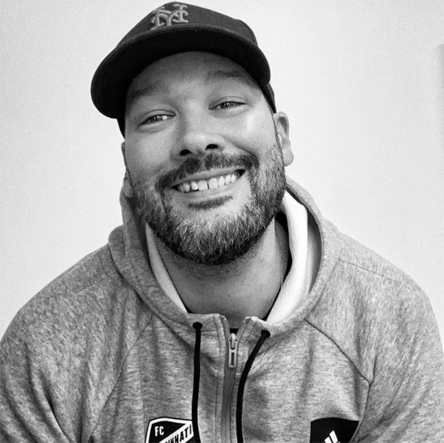 black and white photo of a smiling man with a hat on